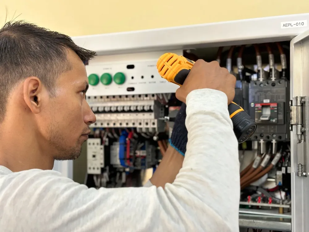 An electrician working inside an open panel
